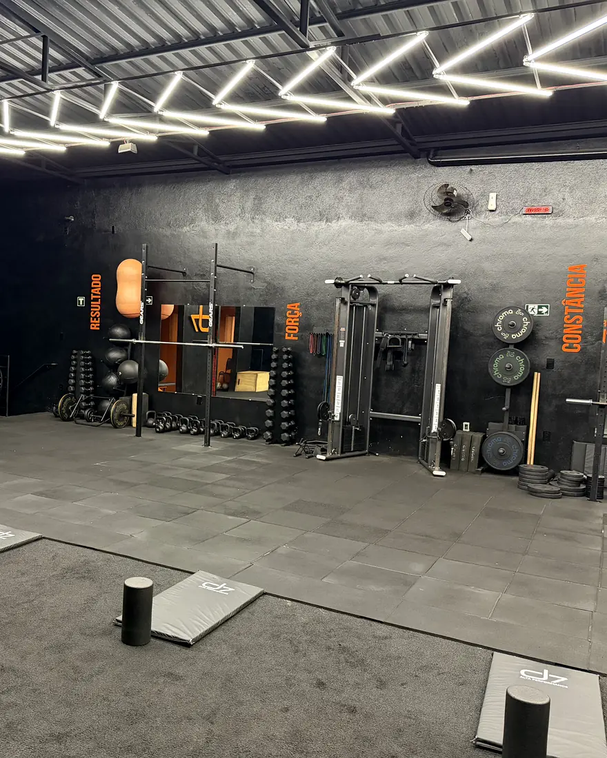 Racks, anilhas e mural de kettlebell laranja no salão do CT D7